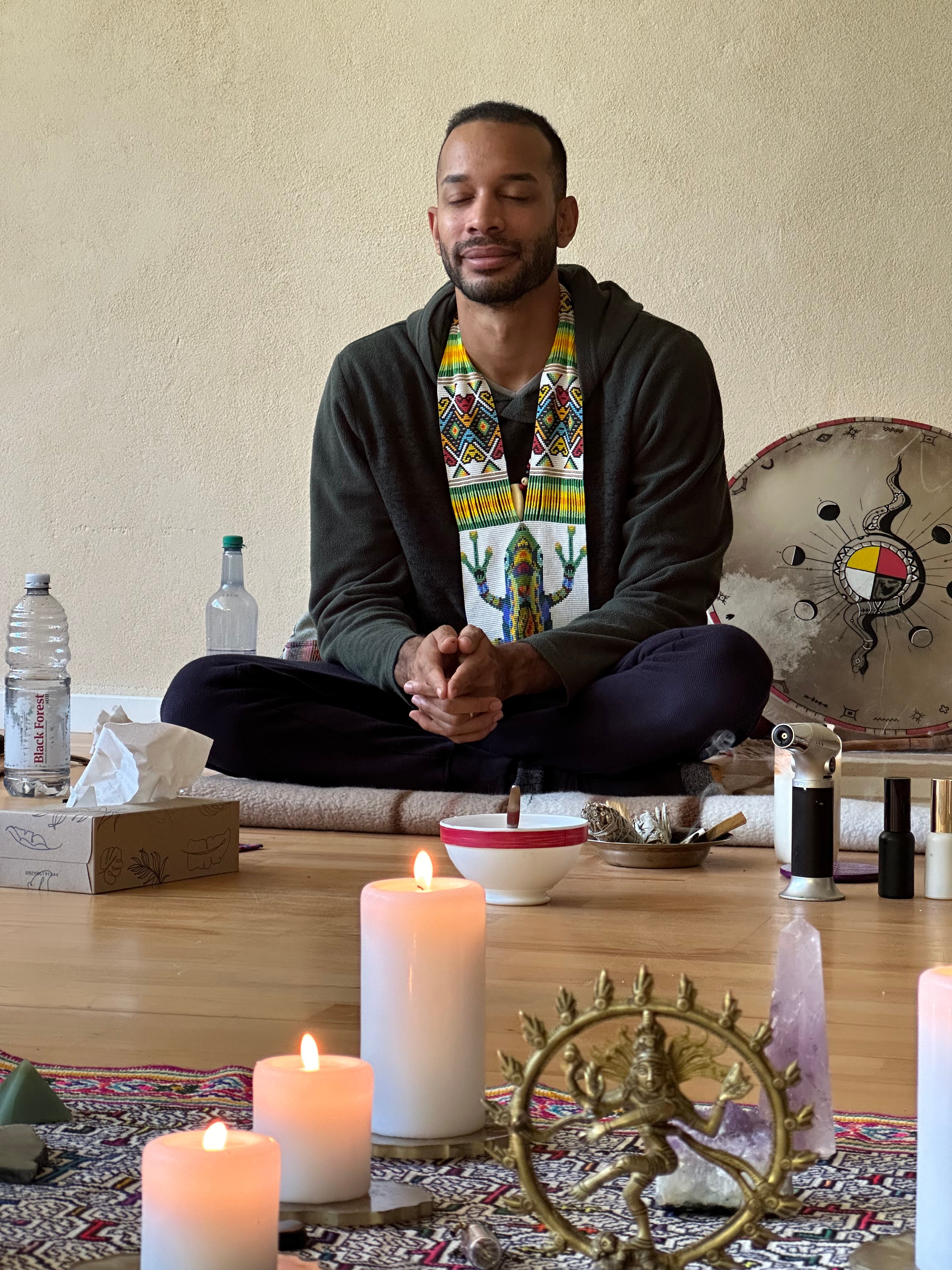 Dominic Henry im Schneidersitz mit Räucherwerk und Kerzen — spirituelle Begleitung